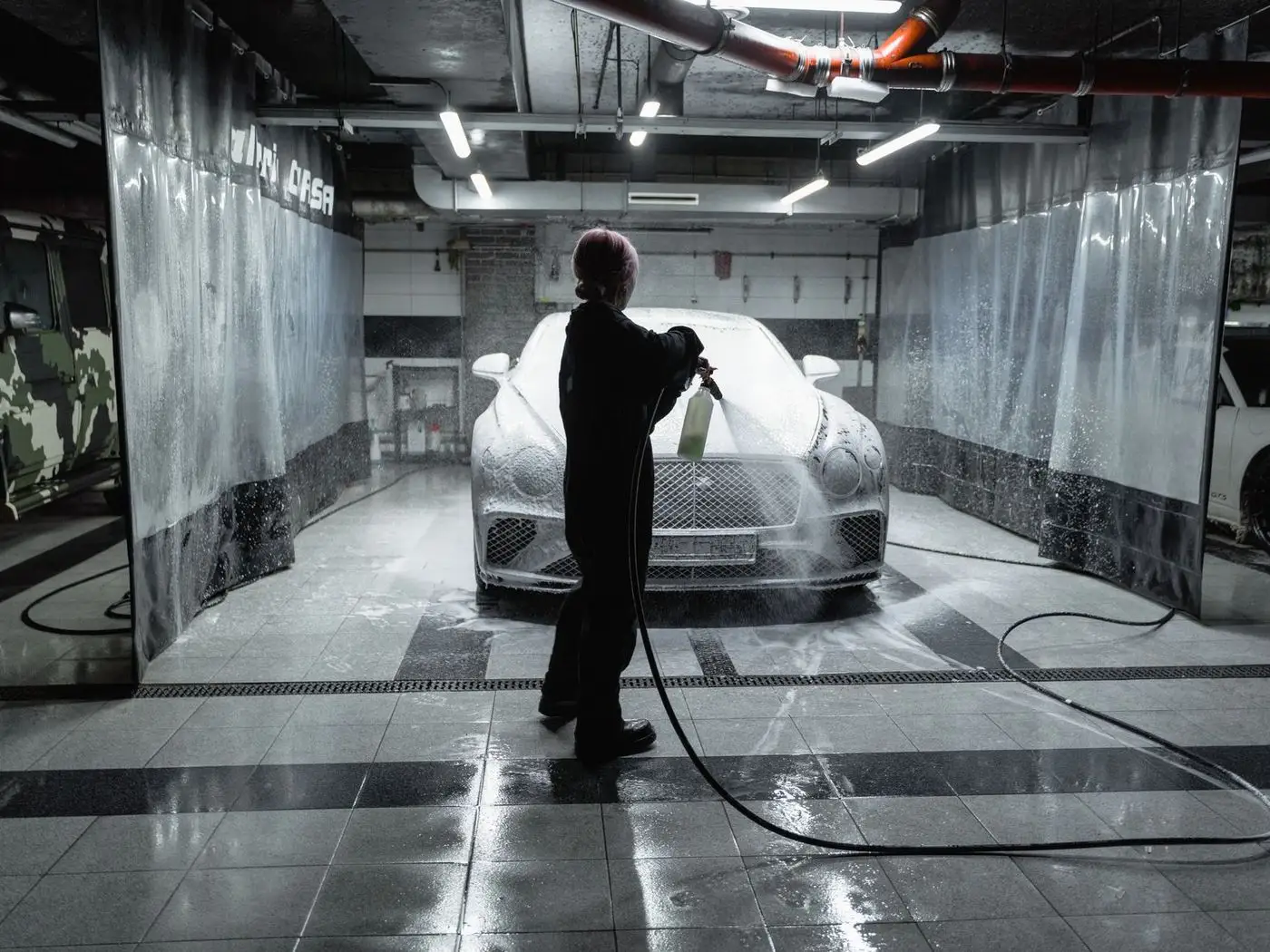 Detailer inspecting the paint of a black car under bright studio lights after a ceramic coating
