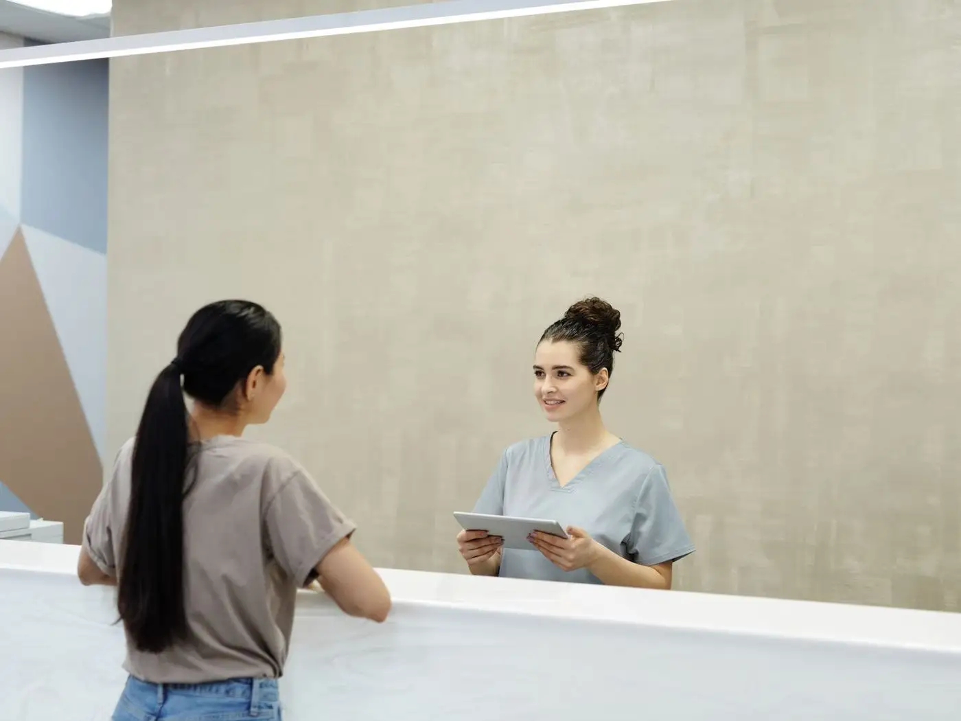 Hospital administrator and a web designer comparing two website layouts on a laptop in a hospital office