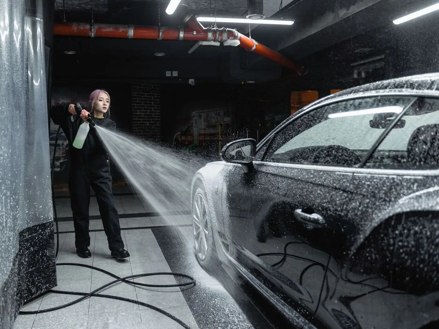Freshly washed SUV in a car wash bay beside a phone showing a booking page with a WhatsApp button