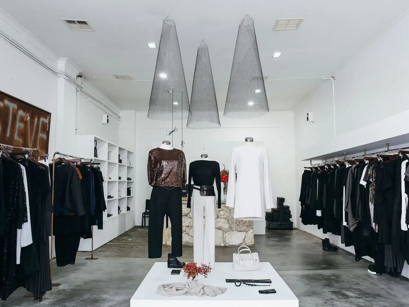 Boutique rail of embroidered suits beside a phone showing a fashion store website