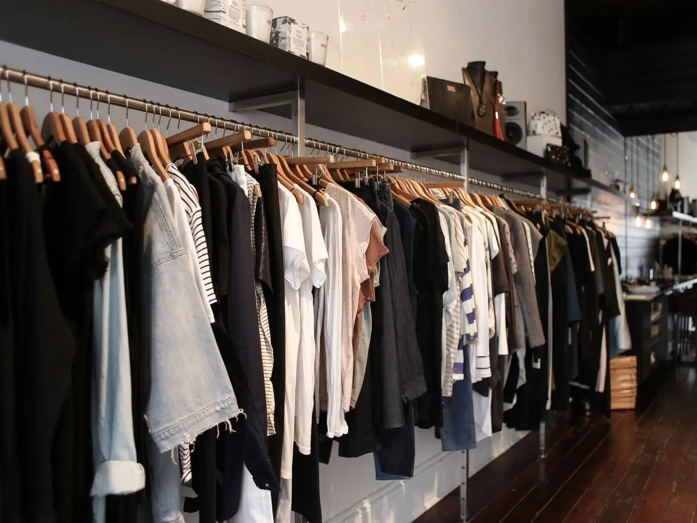 Boutique rail of embroidered suits beside a phone showing a fashion store website