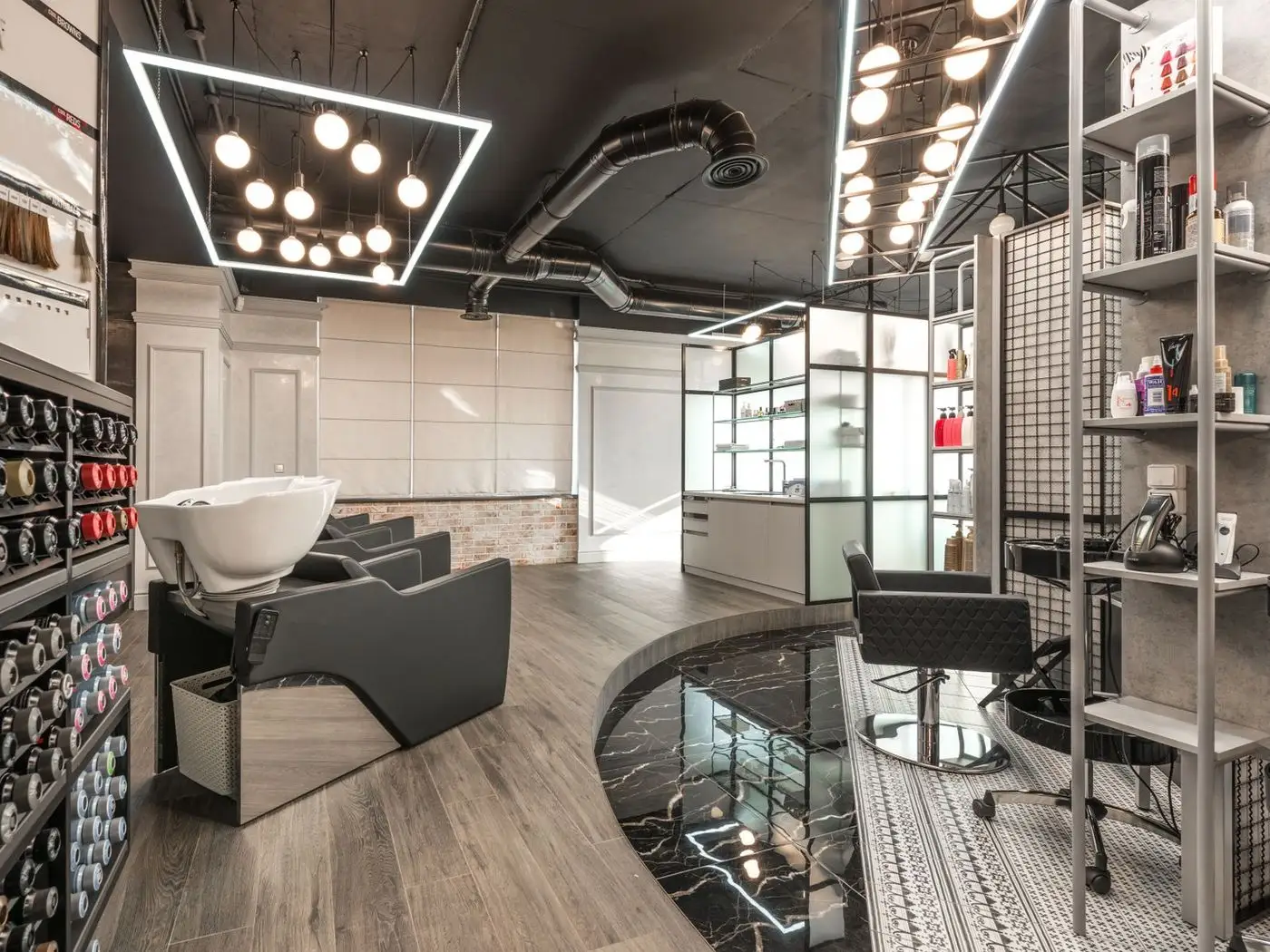 Bright salon interior with styling chairs and a phone showing a salon website with a WhatsApp booking button